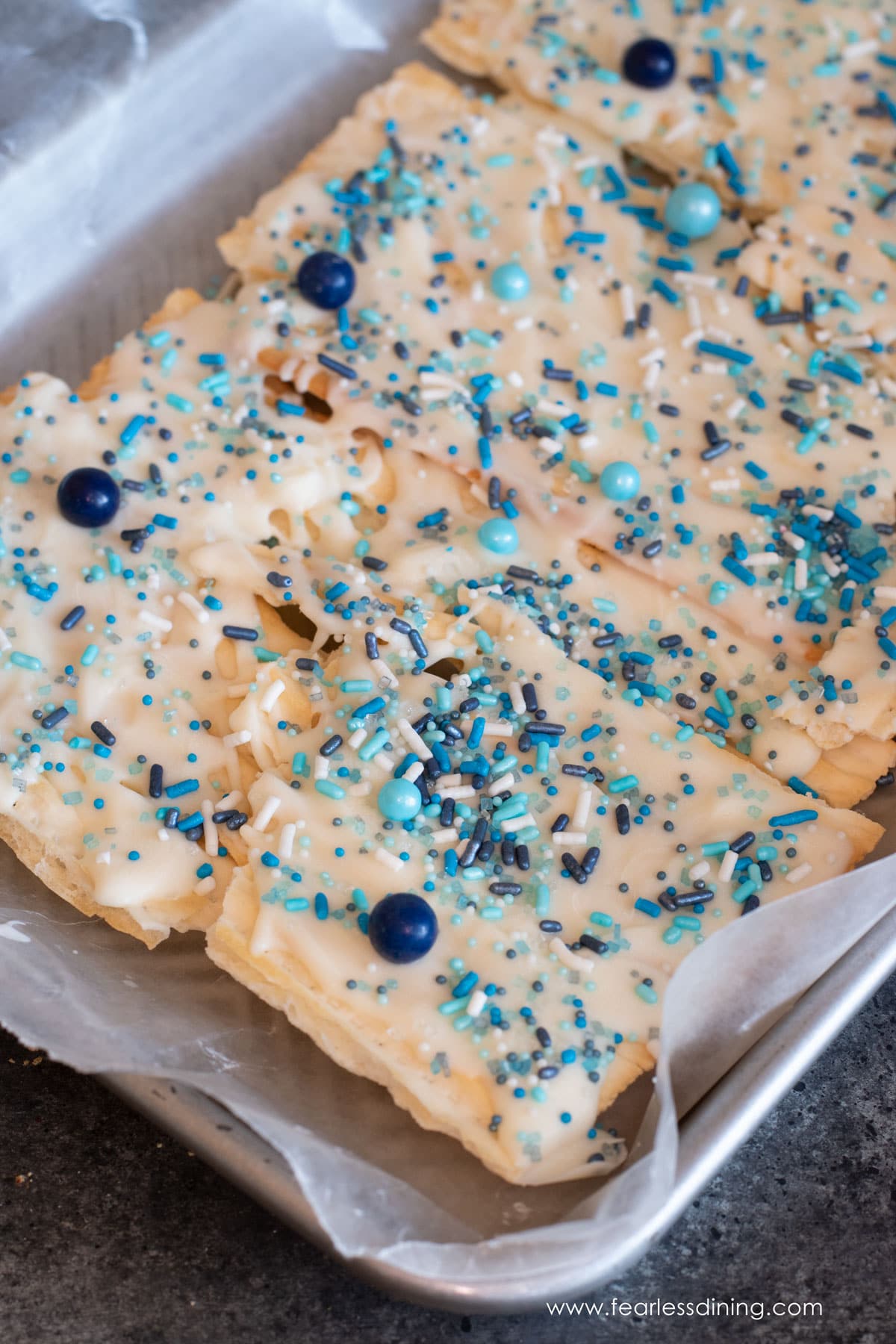 A tray of gluten free matzo crack with white chocolate and blue sprinkles.