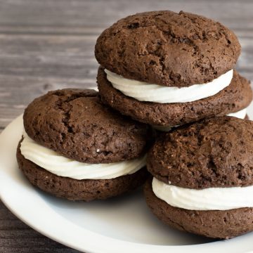 a stack of four whoopie pies on a white plate.