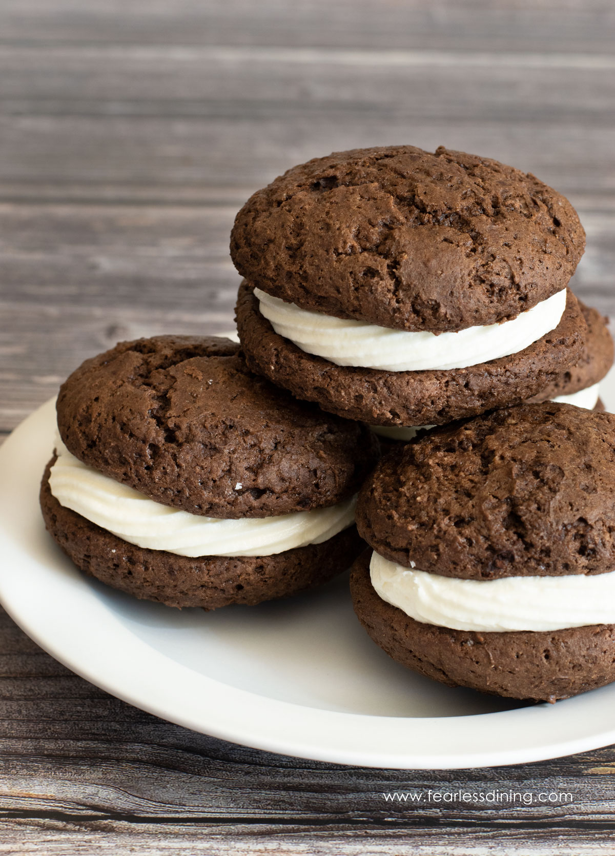 A stack of four whoopie pies on a white plate.