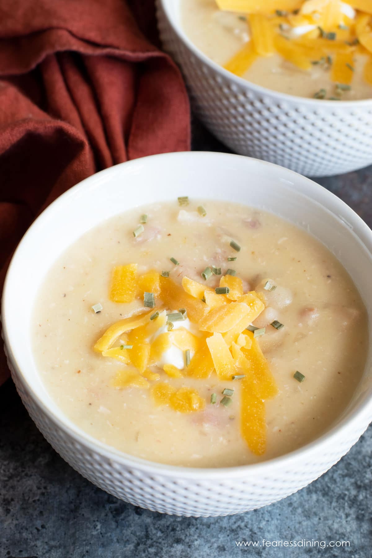 A close up of a bowl of chicken potato soup in a white bowl.