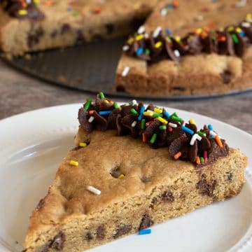 A slice of gluten free cookie cake on a white plate.