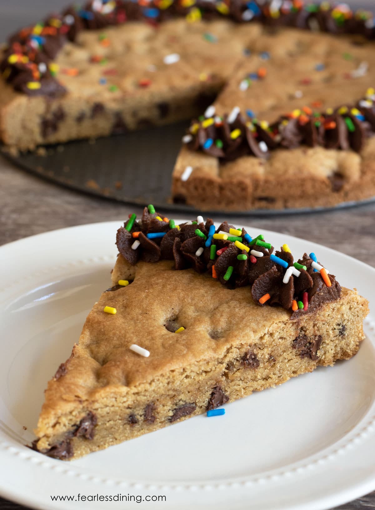 A slice of a decorated gluten free cookie cake on a white plate.
