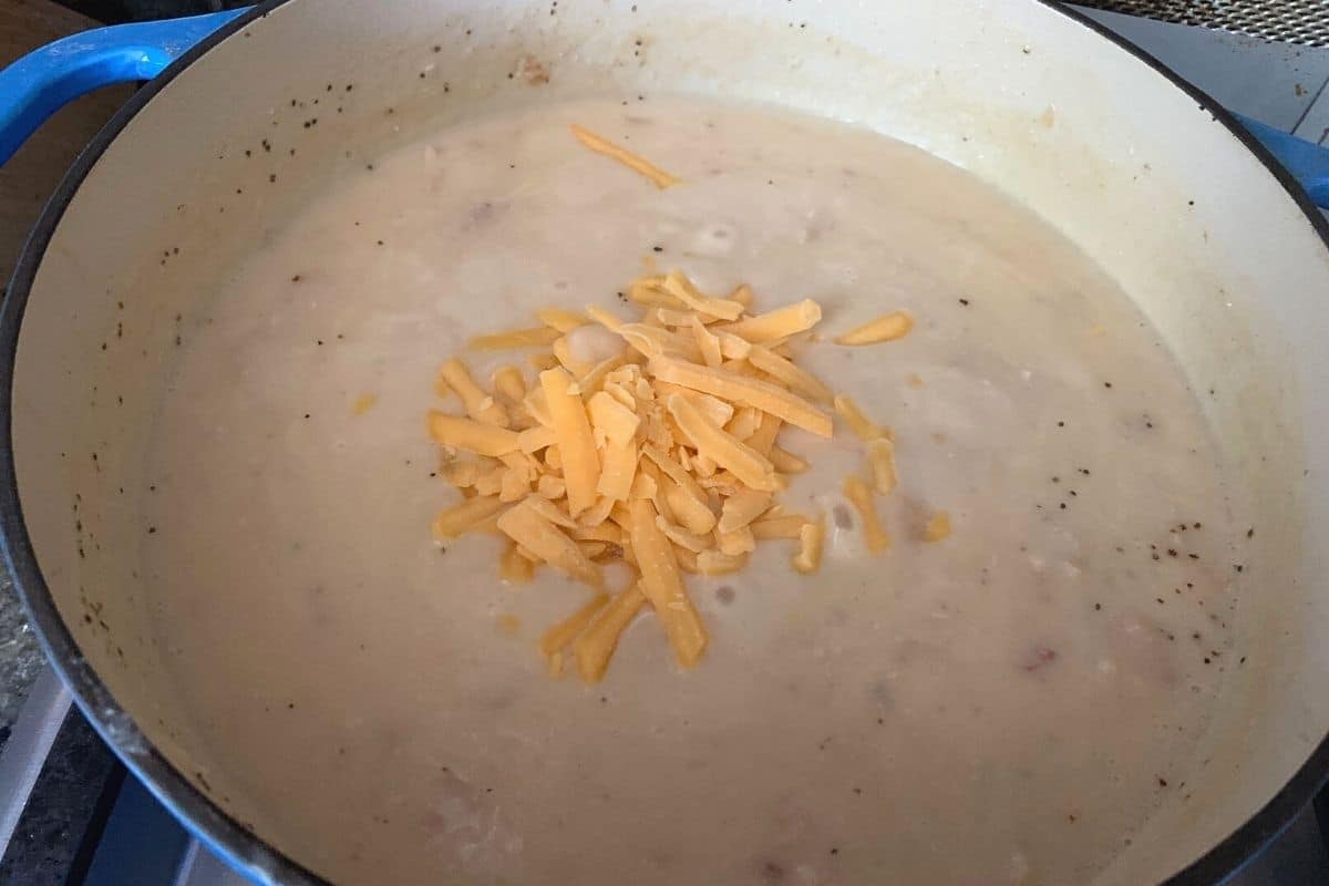 adding cheddar cheese to the soup pot.