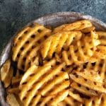 A Pinterest image of a bowl of cooked waffle fries.