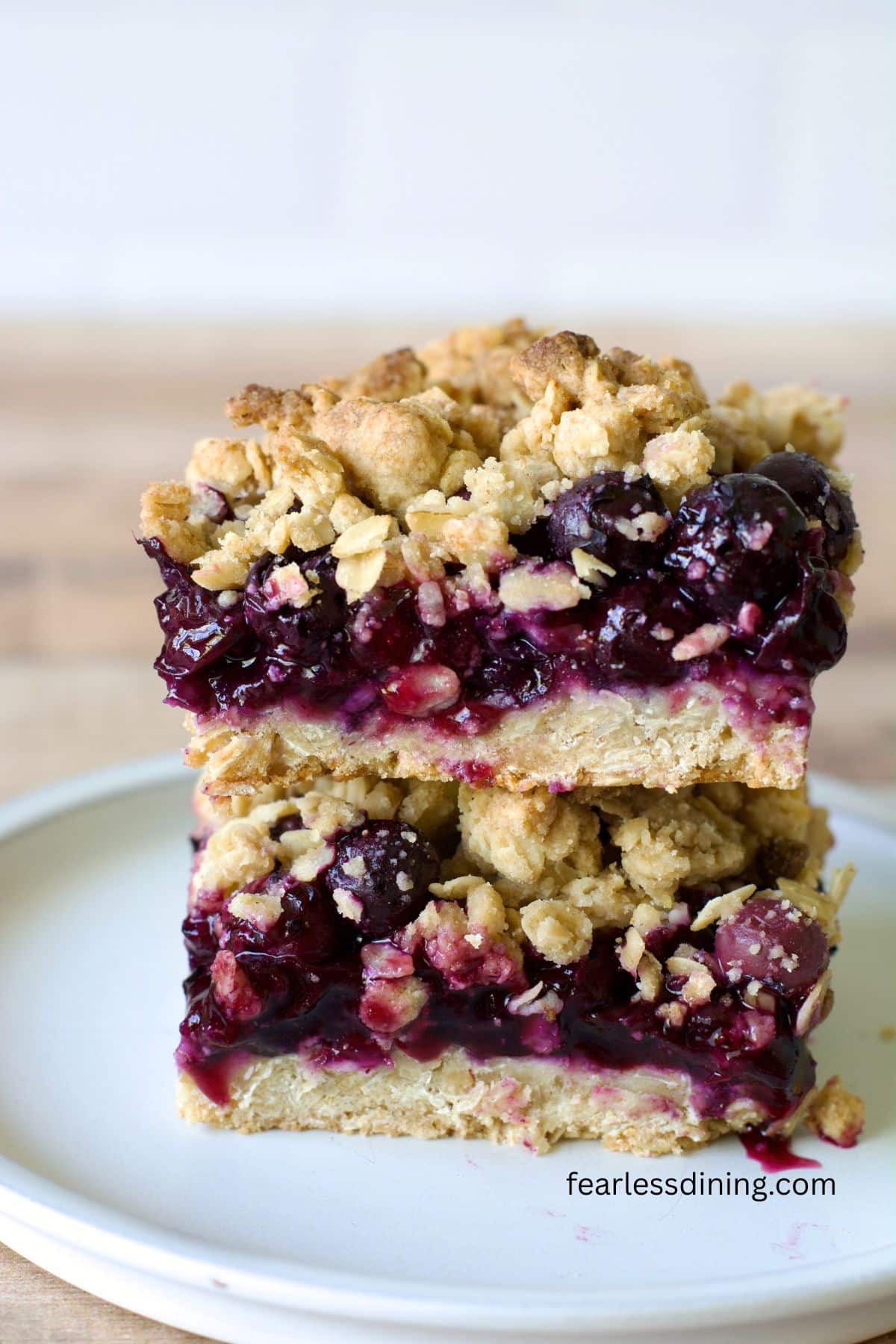 Two gluten-free blueberry bars stacked on top of each other on a plate.