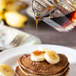 Pouring syrup over a stack of cassava flour pancakes.