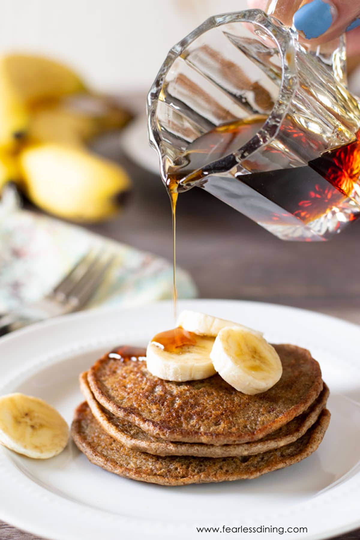 Pouring syrup over a stack of cassava flour pancakes.