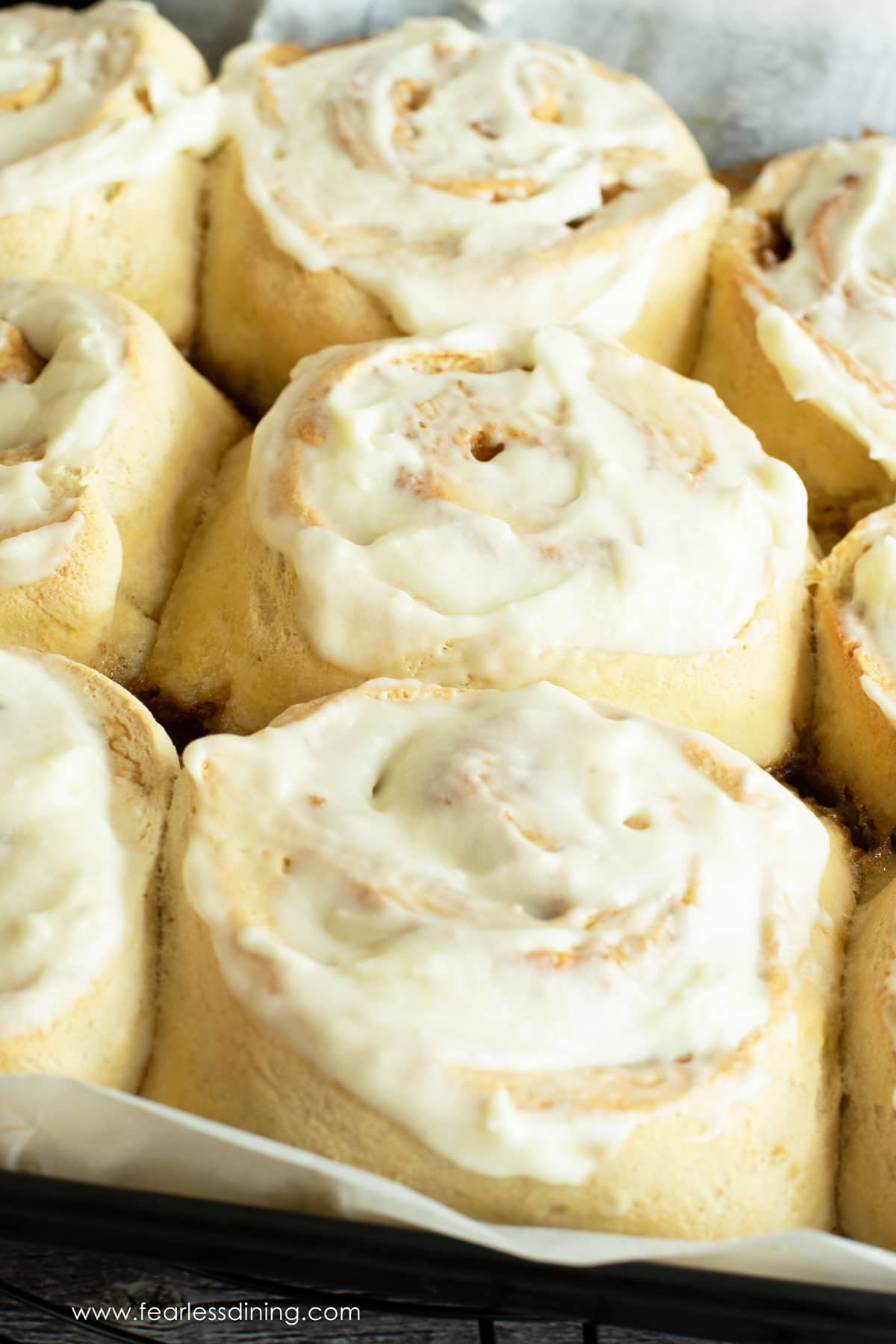 a tray of baked gluten free cinnamon rolls with icing.