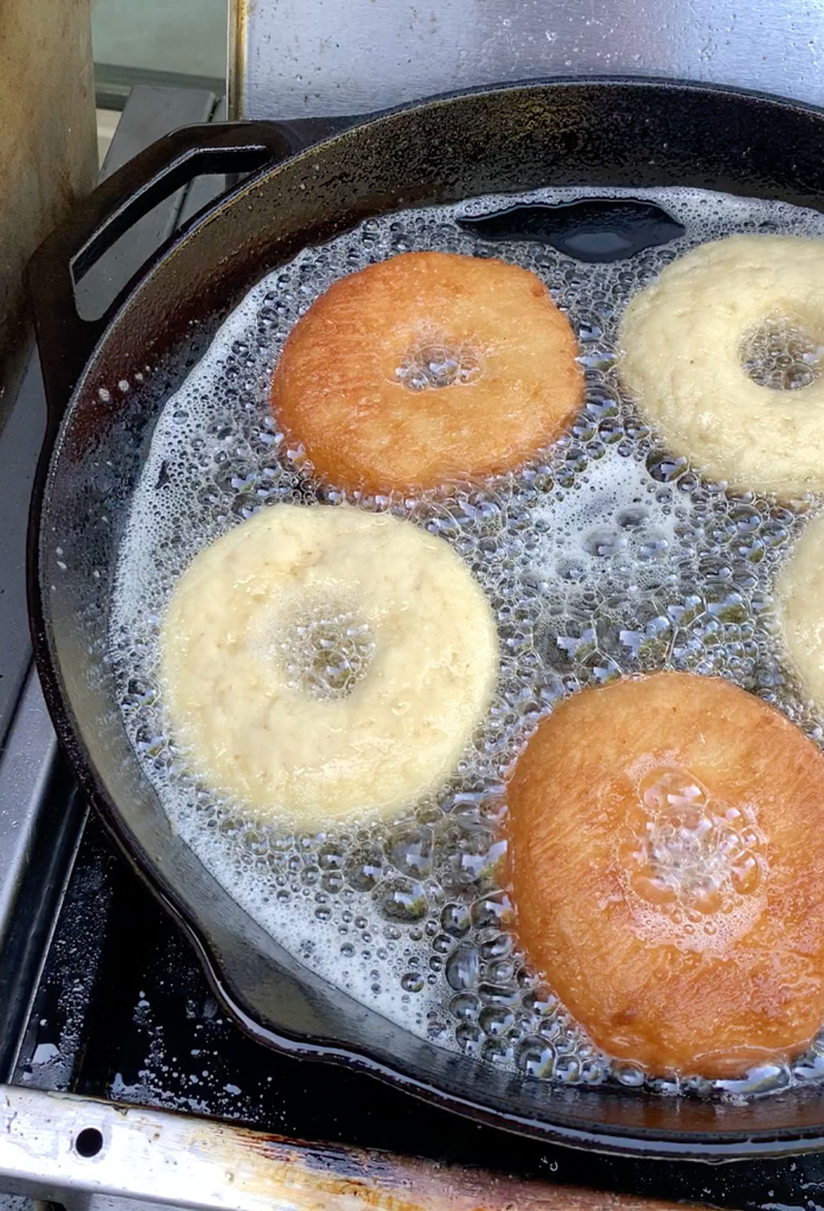 Frying donuts in a large cast-iron skillet.