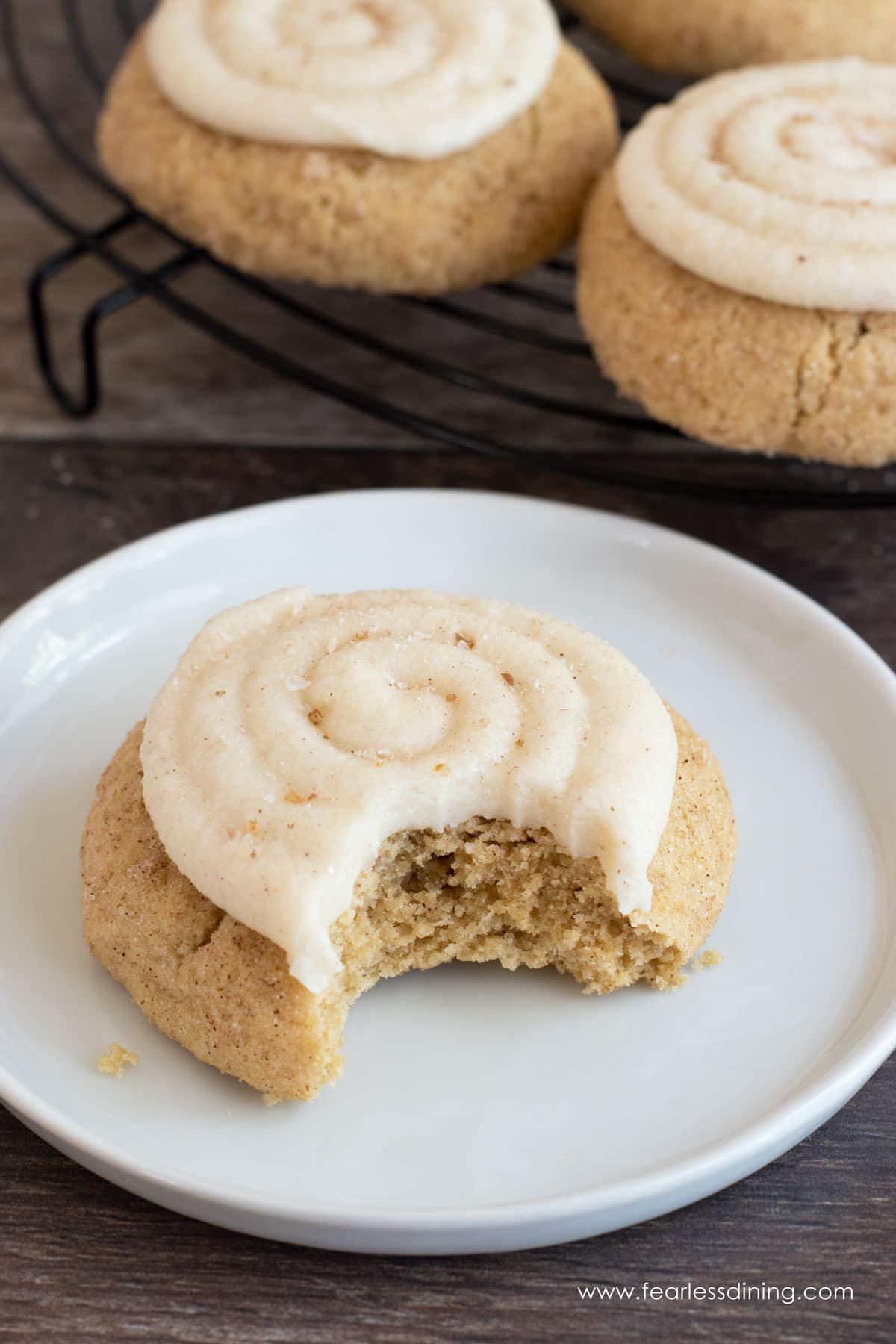 A frosted gluten free crumbl cookie with a bite taken out. 