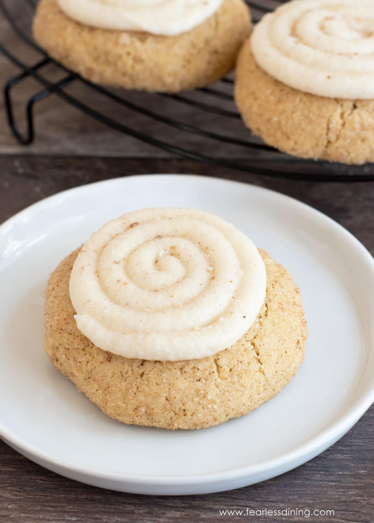 A snickerdoodle crumbl cookie on a small white plate.