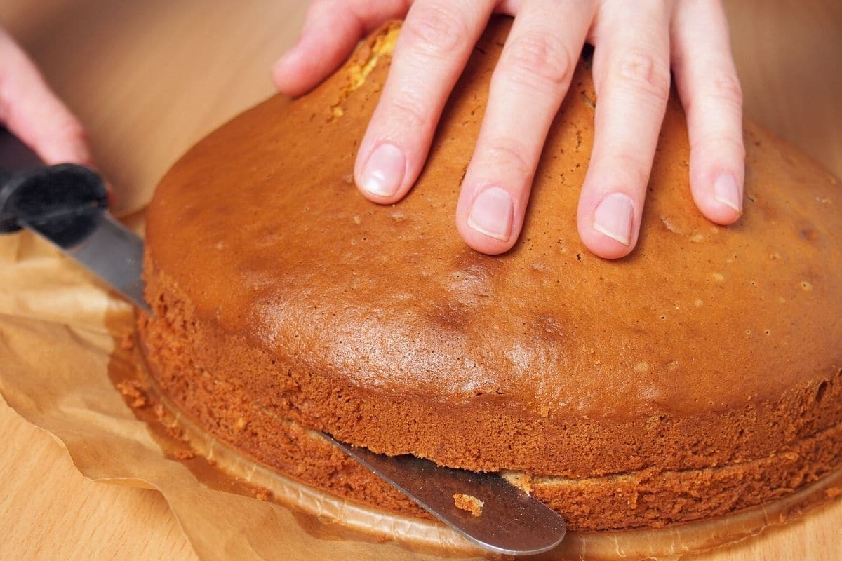 Using a knife to cut the cake into two layers.