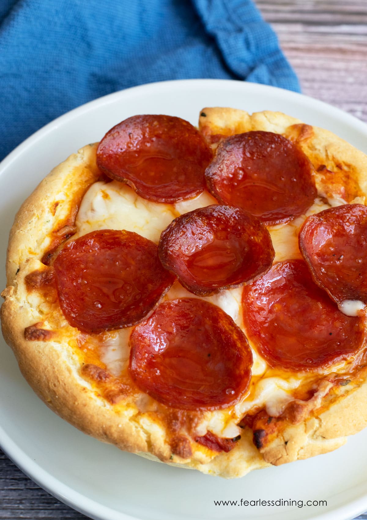 A small deep dish pepperoni pizza on a plate.