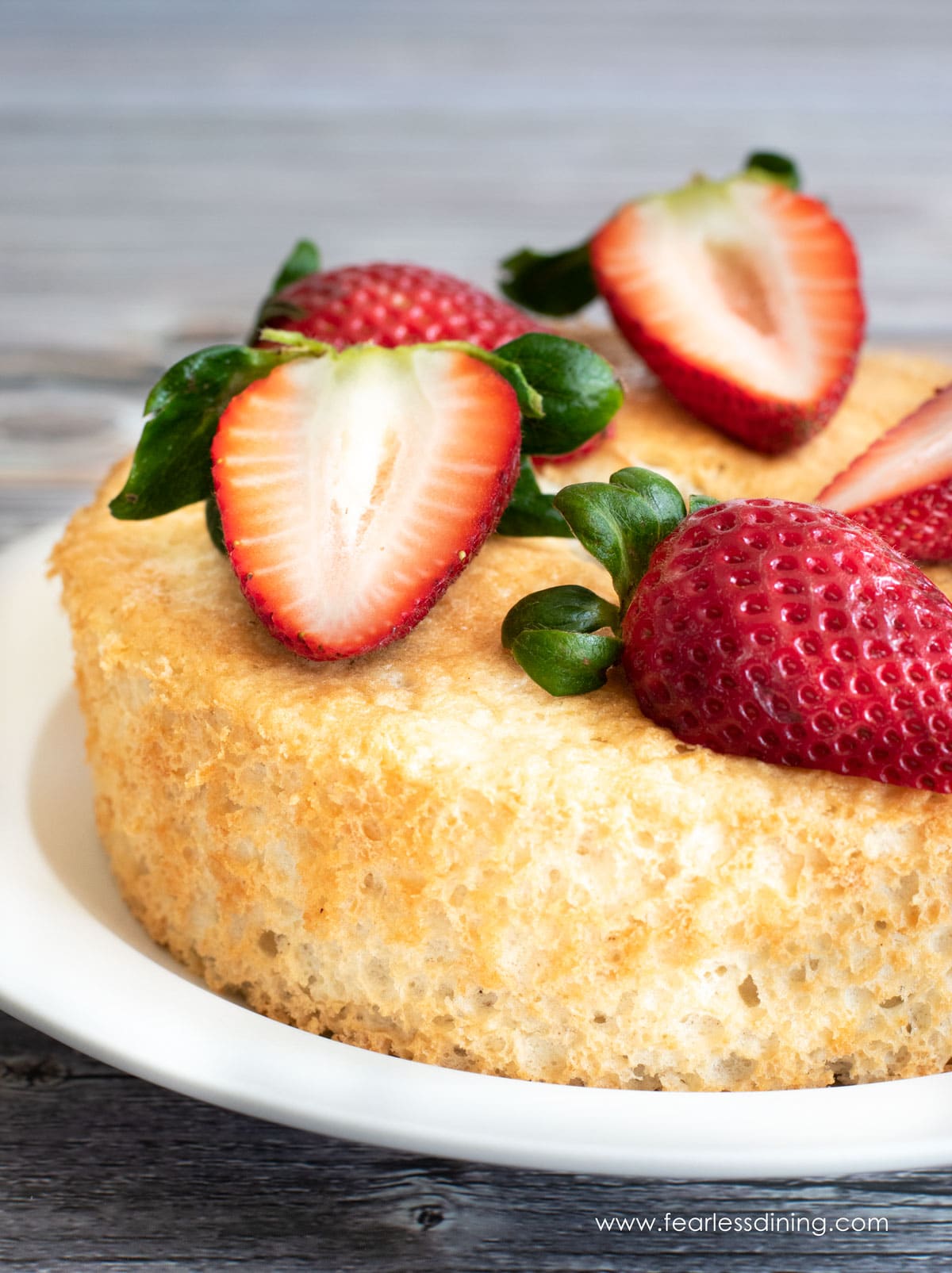 A side view of the angel food cake. It is topped with sliced strawberries.