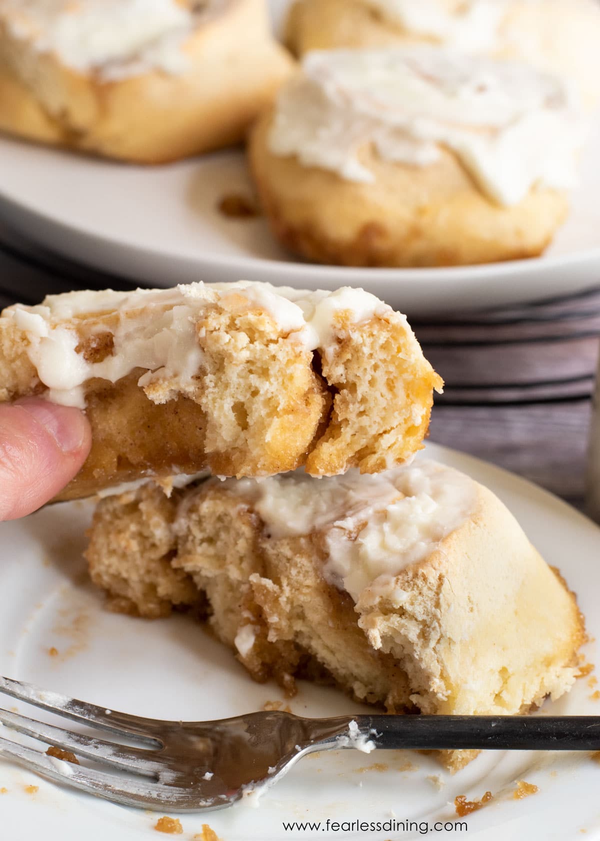 Holding up half of a cinnamon roll.