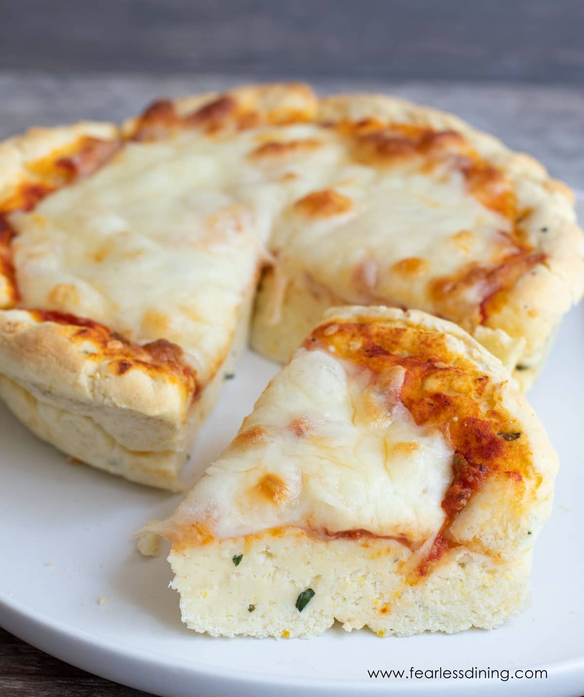 A slice of gluten free deep dish pizza on a plate.