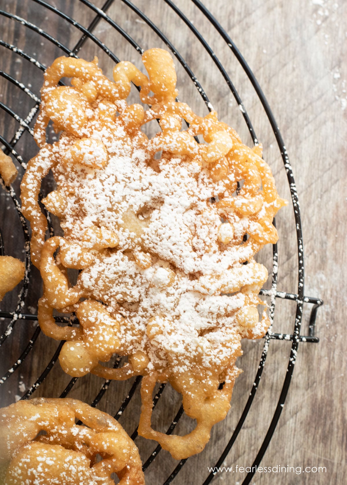 A close up of a fried funnel cake dusted with powdered sugar.