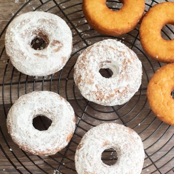 a rack of half powdered half plain donuts.