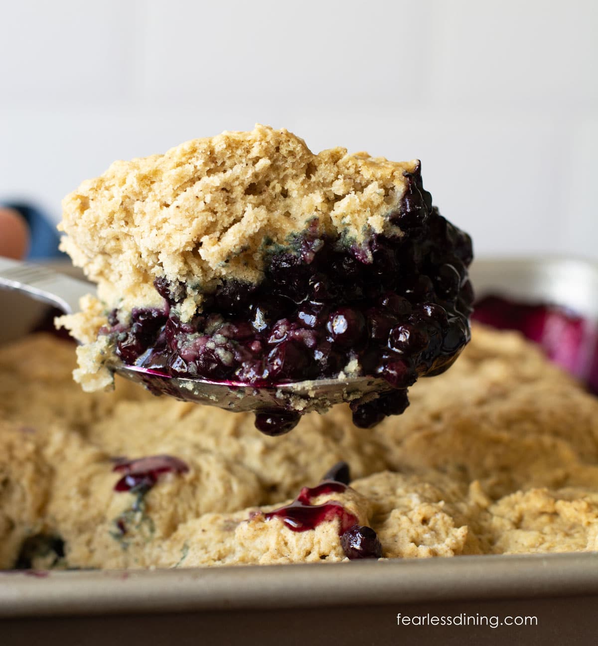 A serving scoop full of gluten-free blueberry cobbler.