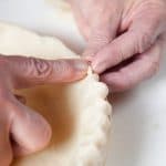 Pinching the pie crust dough with fingers.
