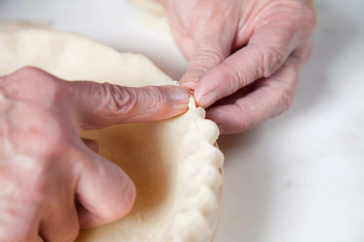 Pinching the pie crust dough with fingers.