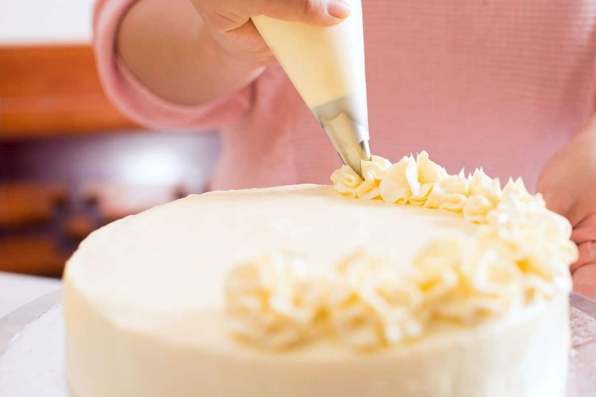 Piping a decorative edge on top of the cake.