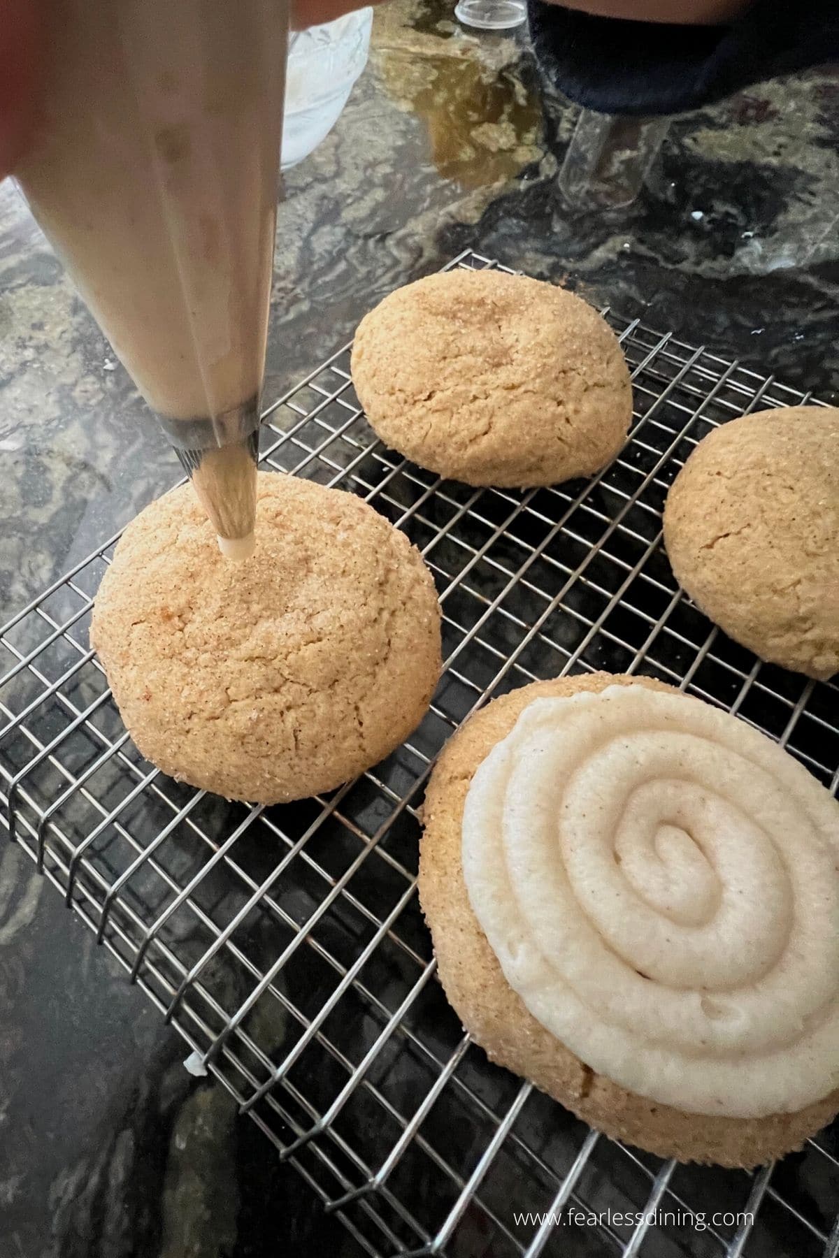 piping cinnamon frosting onto the cookies.