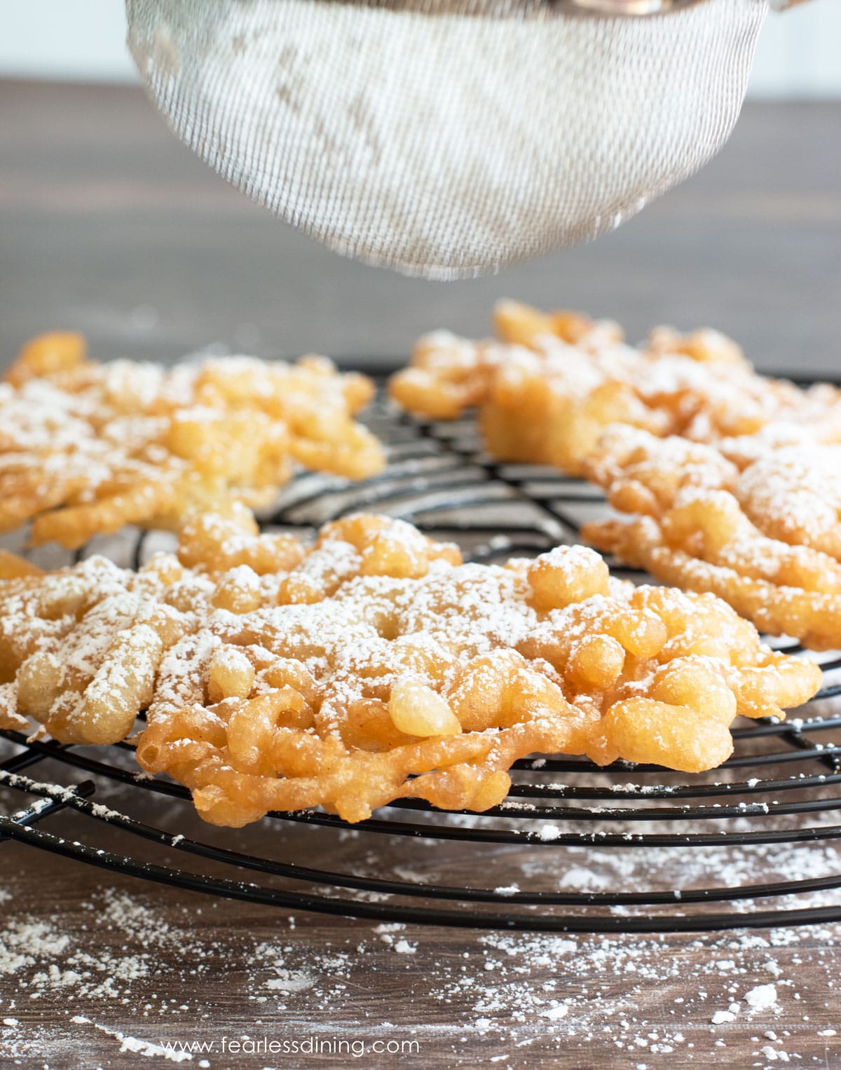 dusting a funnel cake with powdered sugar.