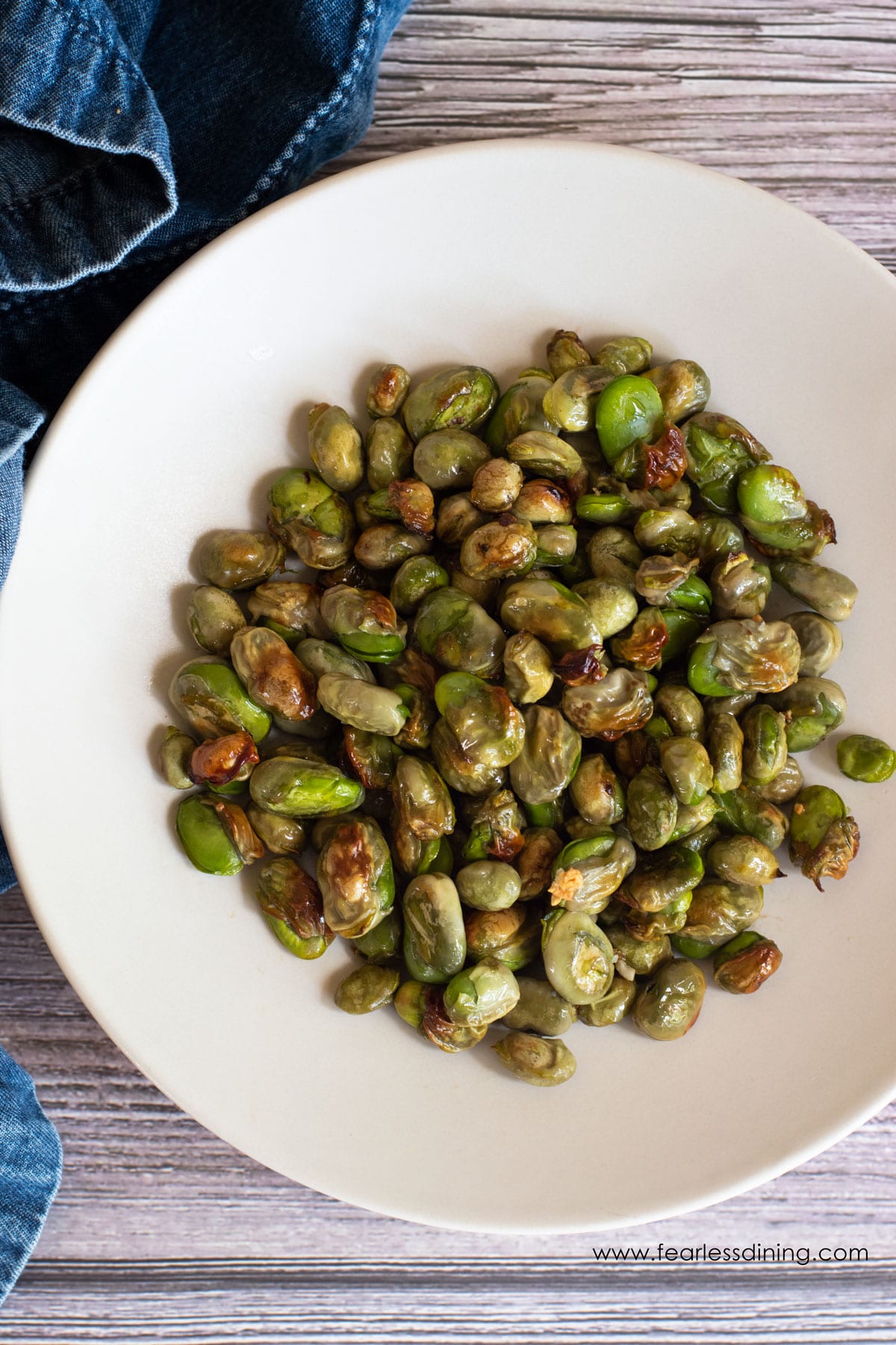 The top view of a bowl of roasted fava beans.