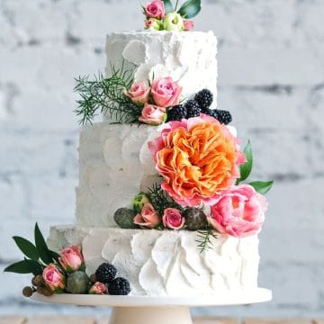 A small three tiered gluten free wedding cake decorated with fresh flowers.