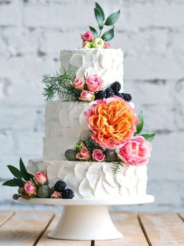 a small three tiered gluten free wedding cake decorated with fresh flowers.