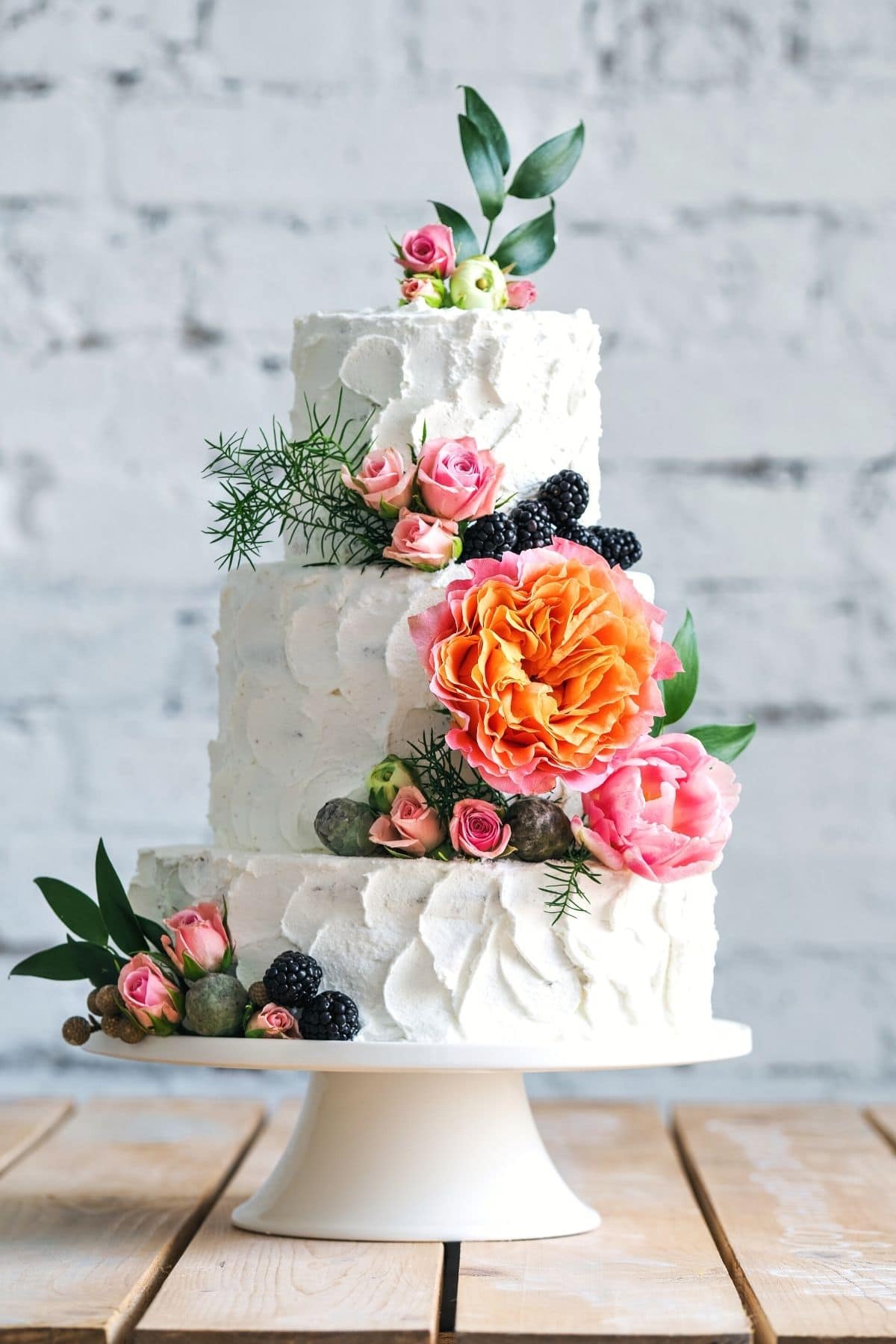 a small three tiered gluten free wedding cake decorated with fresh flowers.