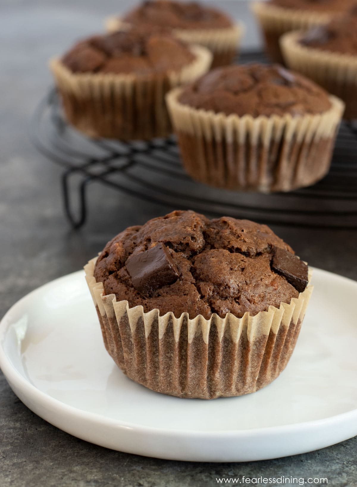 A plate with a chocolate banana muffin on it.