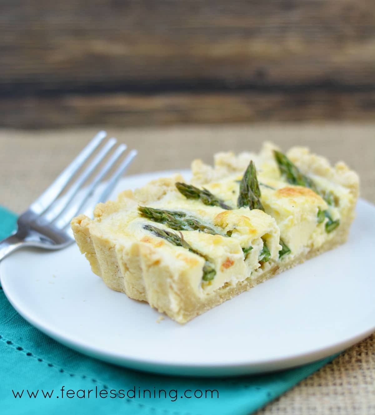 A slice of goat cheese tart on a small white plate.