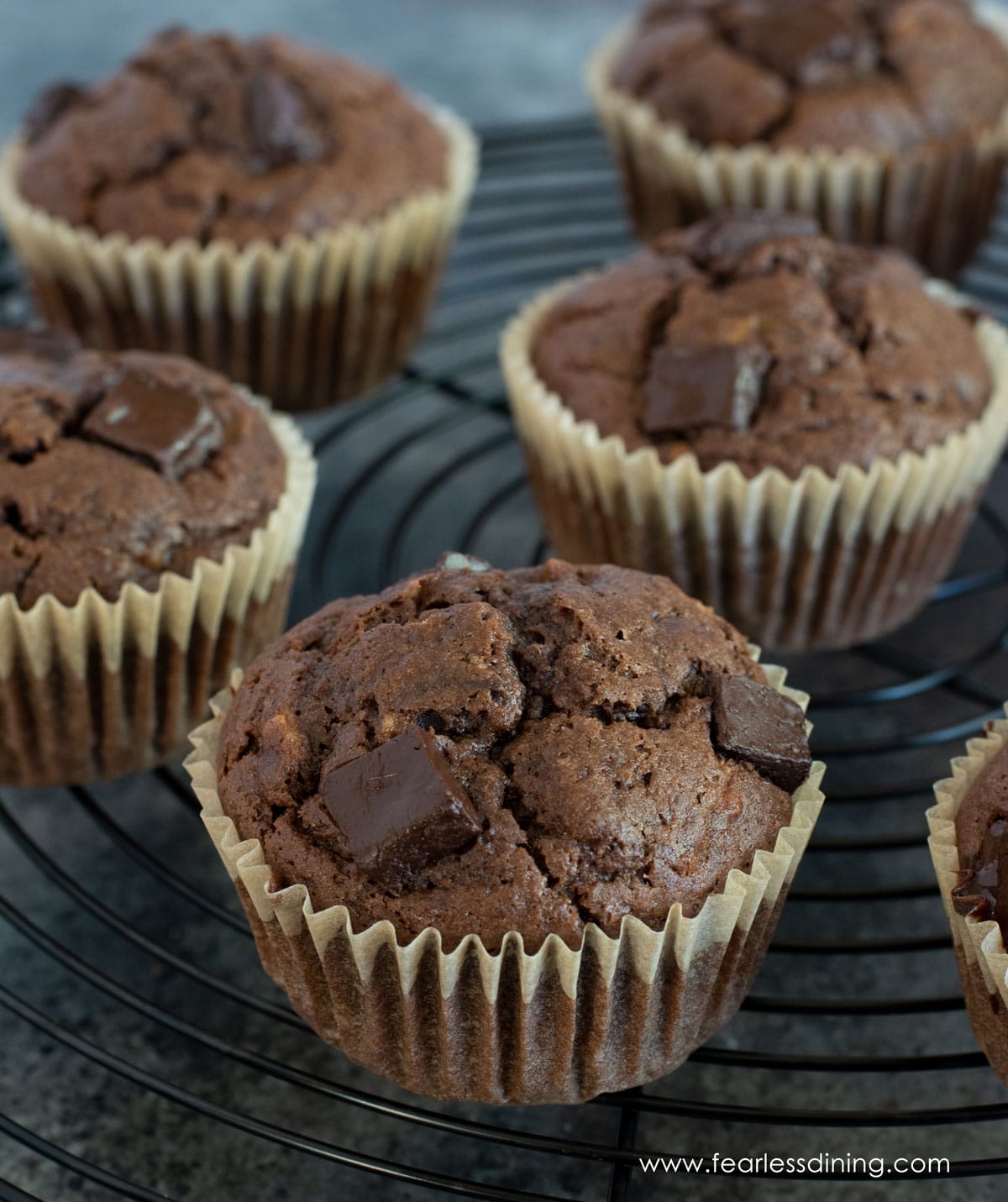 A black wire rack filled with gluten free chocolate banana muffins.