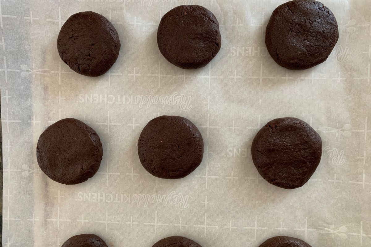 Chocolate cookie balls on a piece of parchment paper.