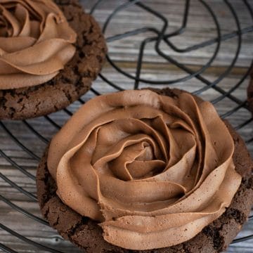 A black wire rack with chocolate frosted cookies on it.