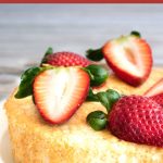 A Pinterest image of a gluten free angel food cake topped with cut fresh strawberries.