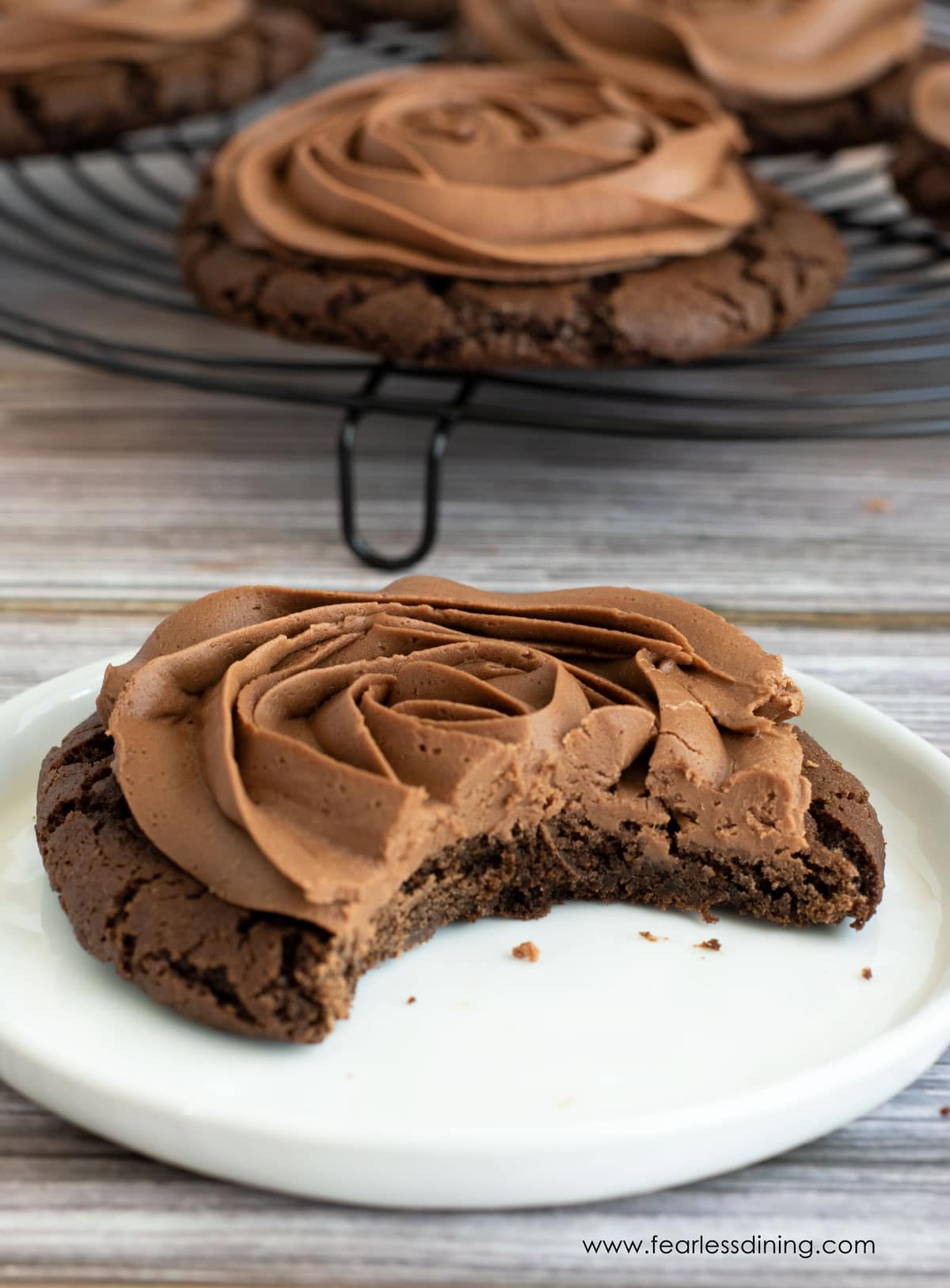 A chocolate frosted cookie with a bite taken out.