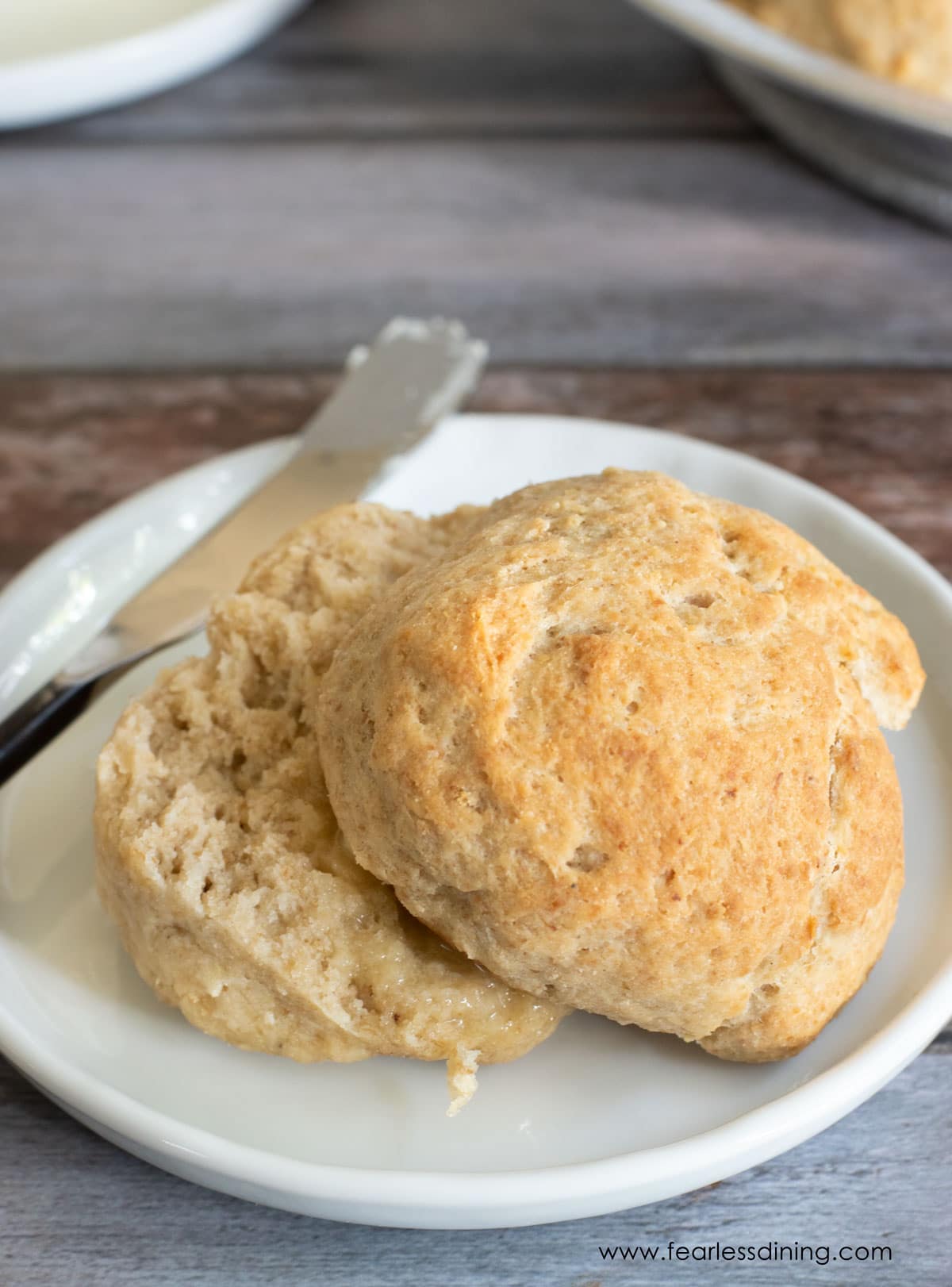 A gluten free yeast roll cut in half on a plate.