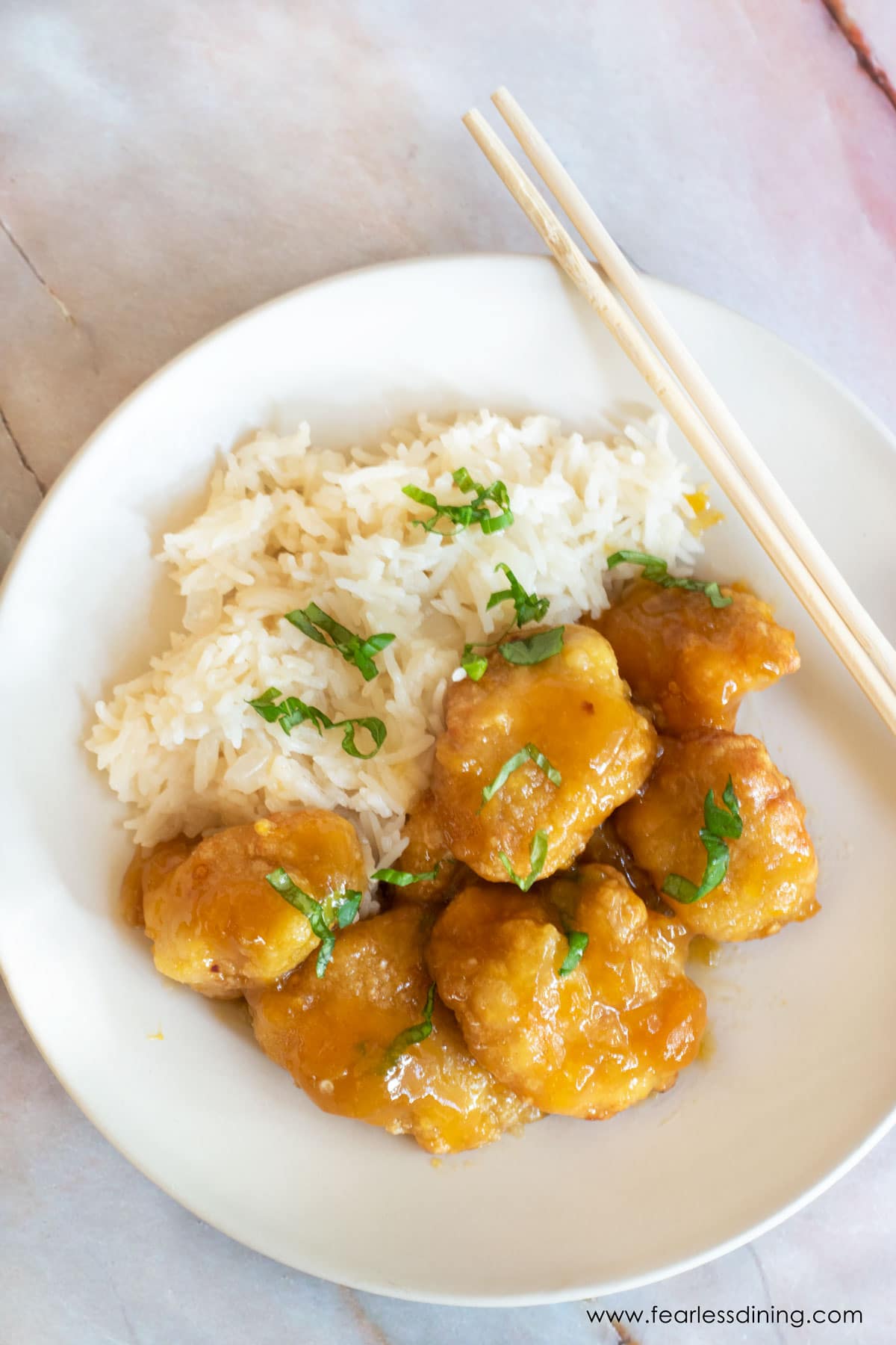 The top view of a plate of orange chicken and white rice.