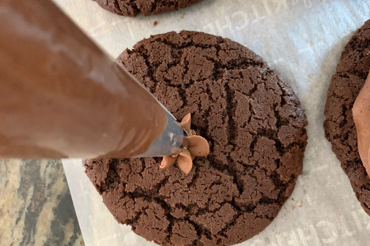 Piping the chocolate frosting onto the cookie.