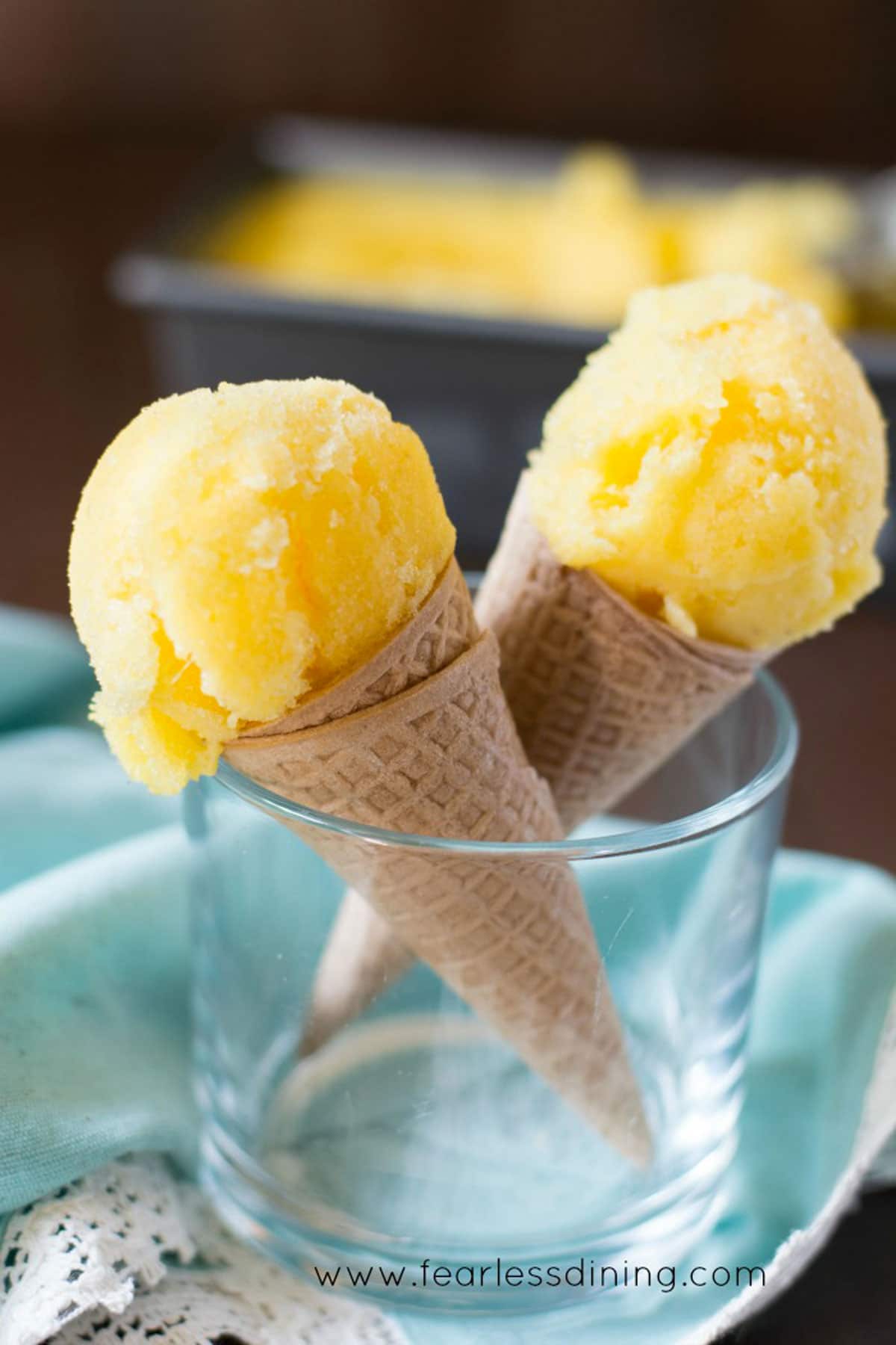 Two pineapple sorbet cones standing in a glass.