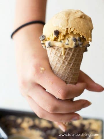 a hand holding an ice cream cone with caramel chip ice cream.