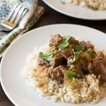 Two plates of lamb stew over rice.