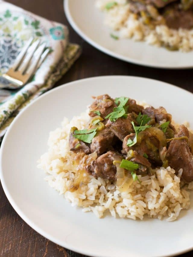 Two plates of lamb stew over rice.