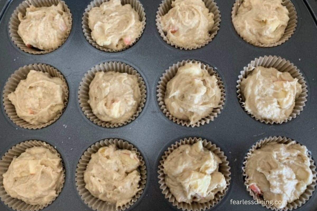The apple muffin batter in a muffin pan, ready to bake.