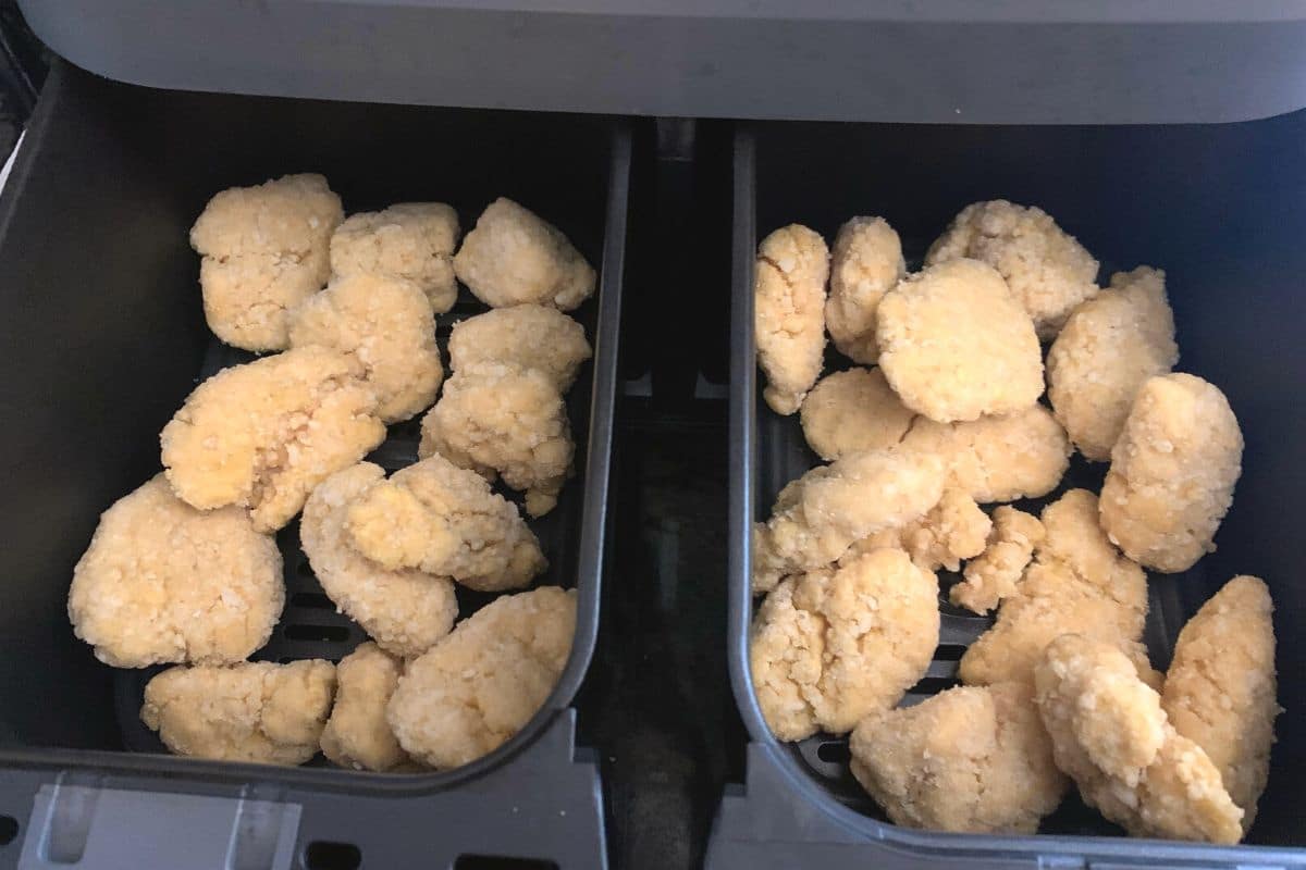 Frozen chicken nuggets in air fryer baskets.