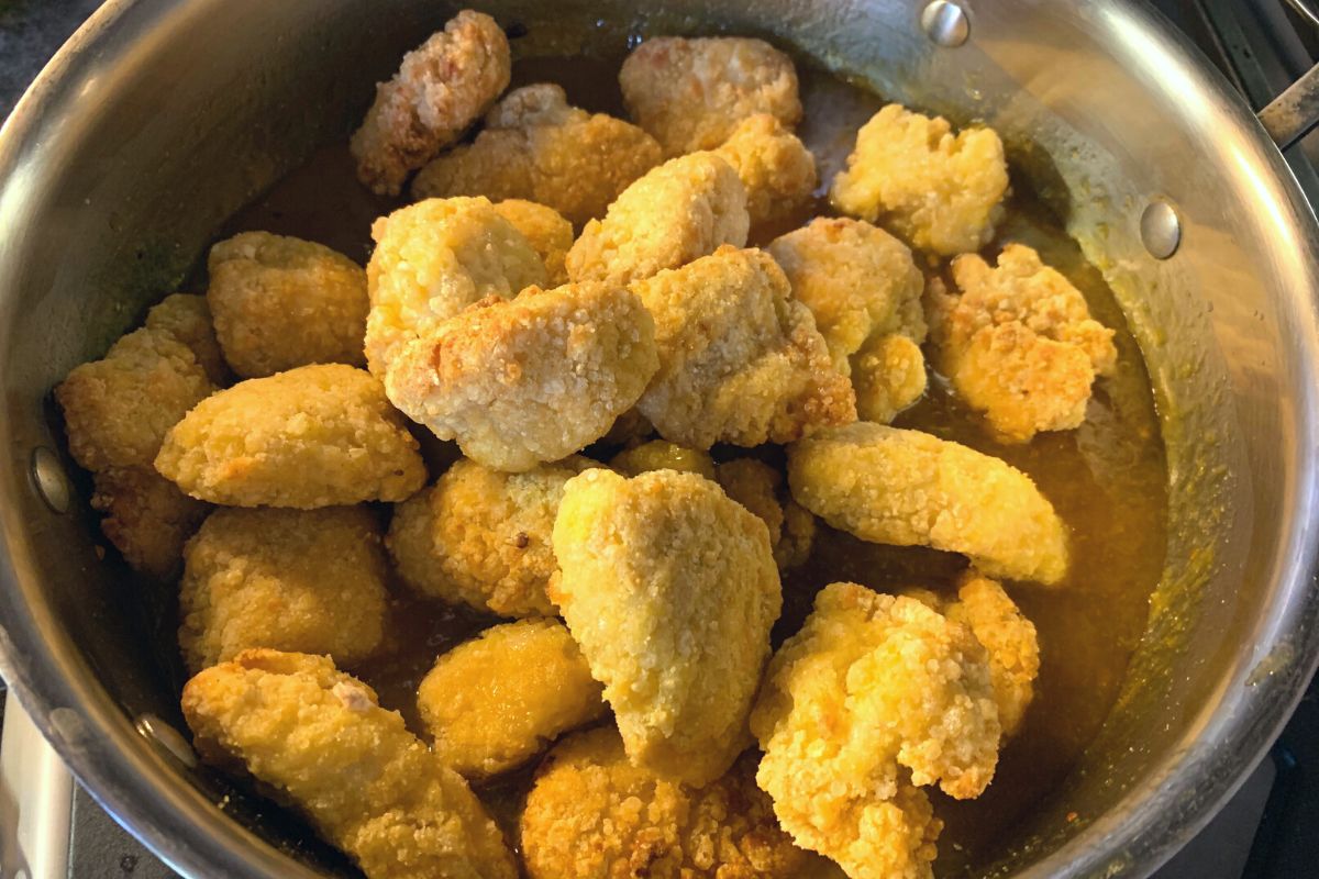 Cooked chicken nuggets about to get mixed into the orange sauce.