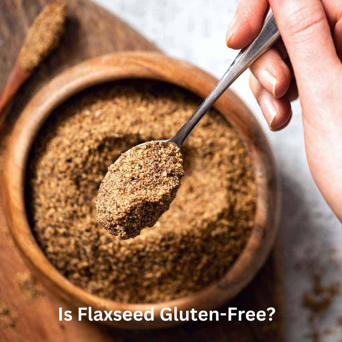 A wooden bowl of ground flaxseed. A spoon is holding up a close up view of the flax.